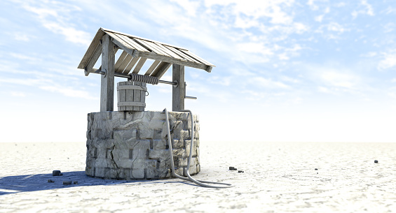 A rundown water well and bucket attached to a rope in a flat waterless landscape on a blue sky background - 3D render