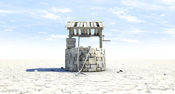 A rundown water well and bucket attached to a rope in a flat waterless landscape on a blue sky background - 3D render