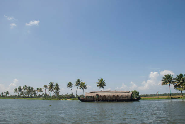 Kumarakom, Kerala, India - October 13, 2010: House boat among the Kerala Channels and its beautiful scenery of water, palm trees, house and fishermen boats