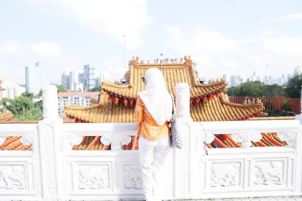 Photo of A confident muslim lady visiting a famous attraction, Thean Hou Chinese Temple in Kuala Lumpur on a very bright sunny day.