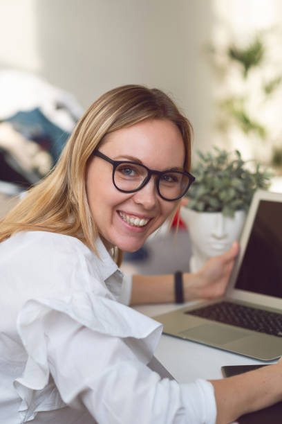 istock Charming blonde woman with glasses smiling at the camera while sitting at a working computer 1191592443