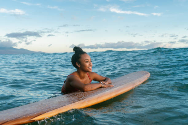 jonge vrouw rusten op haar surfplank wachten op een golf - tropical surf stockfoto's en -beelden
