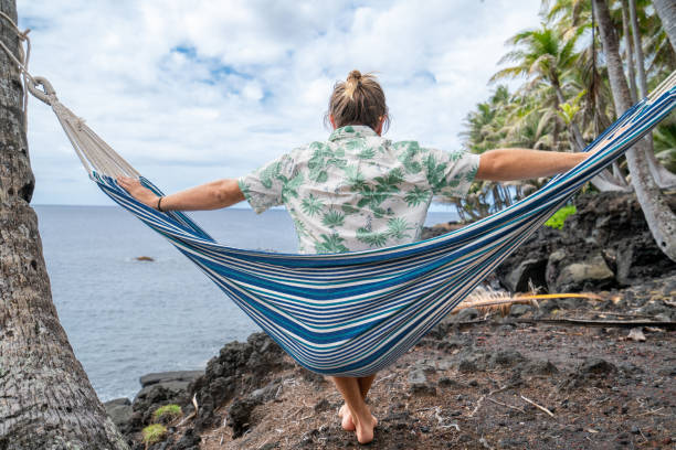 istock Man relaxing on hammock hanging on palms by the beach 1191596718
