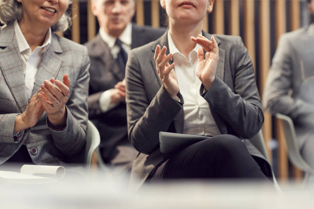 zbliżenie ludzi biznesu w formalnych kurtkach siedzących w widowni i klaszczących ręce podczas powitania trenera na zajęciach szkoleniowych - training business seminar clapping zdjęcia i obrazy z banku zdjęć