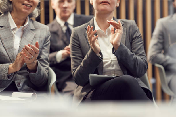 close-up of business people in formal jackets sitting in auditorium and clapping hands while welcoming coach at training class - training business seminar clapping imagens e fotografias de stock