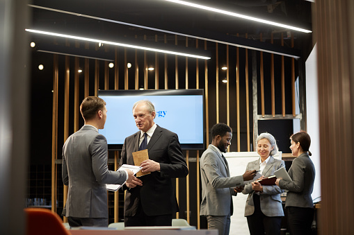 Two mature business people registering for a conference event in a luxury hotel lobby