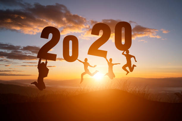istock silhouette number 2020 and people jump on sunset background. 1191598970