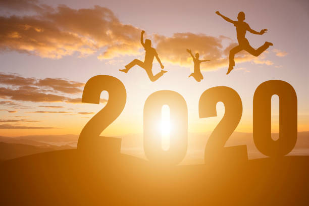 istock silhouette number 2020 and people jump on sunset background. 1191598972