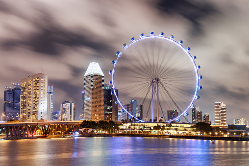 Singapore - February 18, 2017: Awesome night view of the Singapore Flyer and Marina Bay. Amazing colorful cityscape. The giant observation wheel is a popular tourist attraction of Asia.
