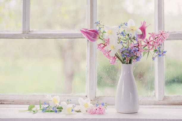 spring flowers in white vase on old windowsill