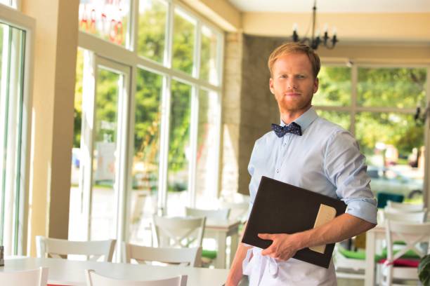 istock Portrait of confident young waiter holding menu while standing at restaurant 1191601602