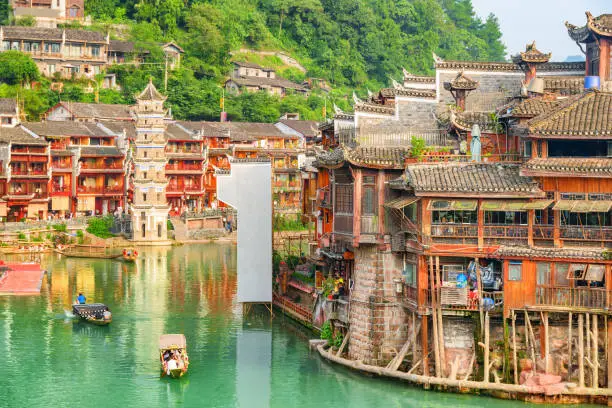 Amazing view of traditional wooden tourist boats on the Tuojiang River (Tuo Jiang River) in Phoenix Ancient Town (Fenghuang County), China. The Wanming Pagoda is visible at left.