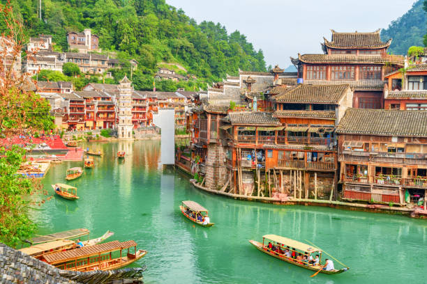 Fabulous view of wooden tourist boats on the Tuojiang River Fabulous view of traditional wooden tourist boats on the Tuojiang River (Tuo Jiang River) in Phoenix Ancient Town (Fenghuang County), China. The Wanming Pagoda is visible in background. fenghuang county photos stock pictures, royalty-free photos & images