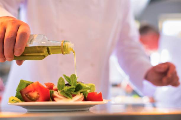 istock Mature chef using pouring oil on salad in plate at restaurant 1191604391