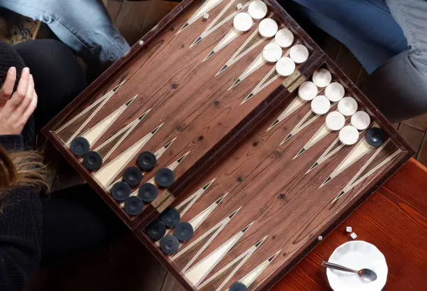 Flat lay of two people playing backgammon game while drinking tea. Top view.