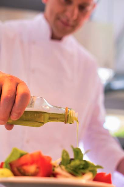 istock Mature chef using pouring oil on salad in plate at restaurant 1191605819