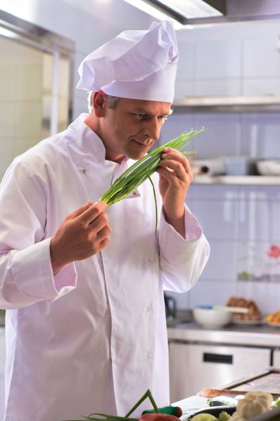 istock Confident mature chef smelling onion leaves at kitchen restaurant 1191606197