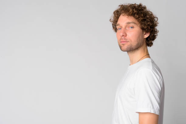 istock Profile view of handsome man with curly hair looking at camera 1191607590