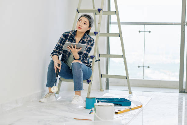 istock Woman watching tutorial on walls painting 1191610981