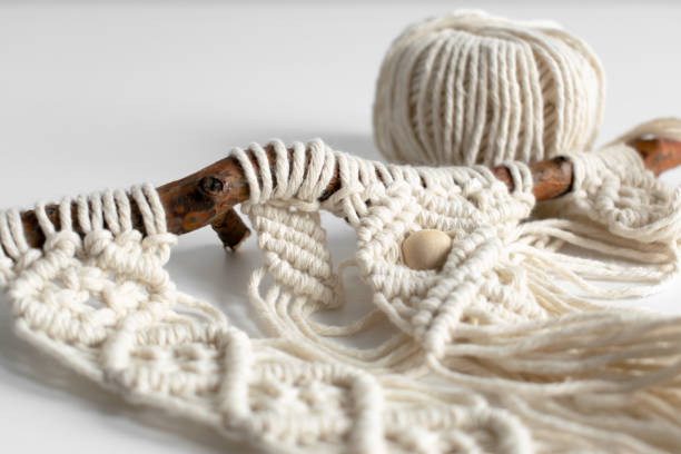 istock Handmade macrame braiding and cotton threads on rustic wooden stick. Boho image good for macrame and rustic handicrafts banners and advertisement 1191611790