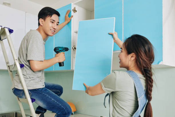 Couple assembling cupboard together Cheerful young Asian woman giving blue door to her husband assembling kitchen cupboard painting kitchen cabinets stock pictures, royalty-free photos & images