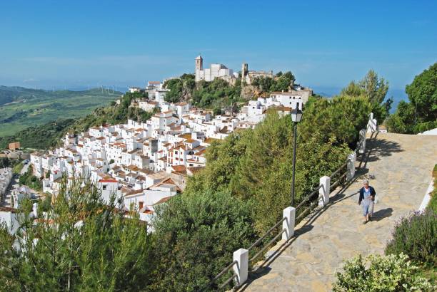 Street leading to white town, Casares, Spain. Spanish lady walking along an elevated pathway with the traditional white village to the rear, Casares, Malaga Province, Andalucia, Spain, Western Europe. casares photos stock pictures, royalty-free photos & images