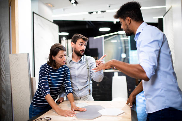 istock A woman putting some ideas together on a couple of hexagonal tile samples on a table with her husband and a store clerk in a bathroom equipment and accessories shop 1191616081