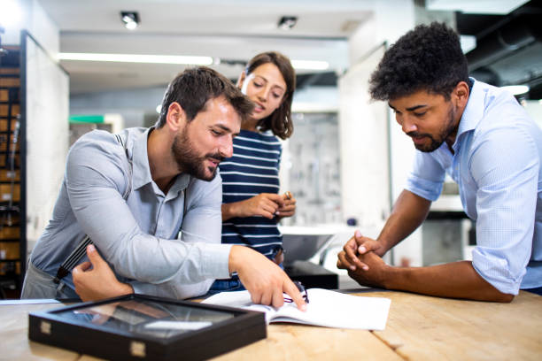 istock Store salesman having a discussion with young shopping couple while leaning on the table with a catalog in the store 1191616091