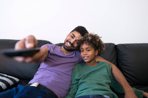 istock Father and daughter sitting in comfortable sofa and watching television. Man hugging his daughter and holding remote control watching TV. Leisure and spare time. 1191616689