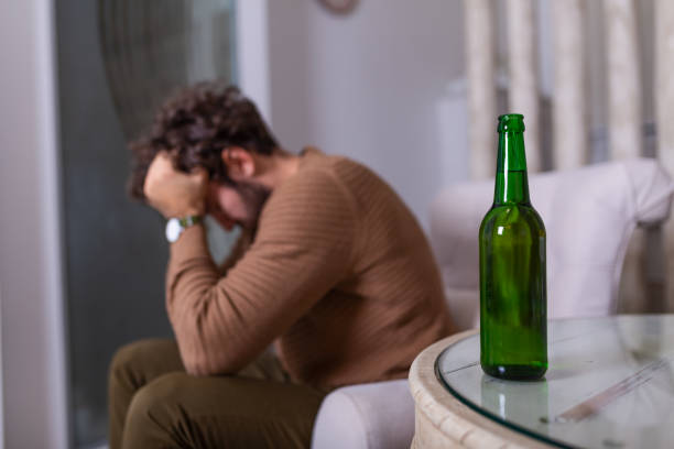 depressed sad young addicted man feeling bad drinking beer alone at home, stressed frustrated lonely drinker alcoholic suffer from alcohol addiction having problem, alcoholism concept - eastern european caucasian one person alcoholism imagens e fotografias de stock