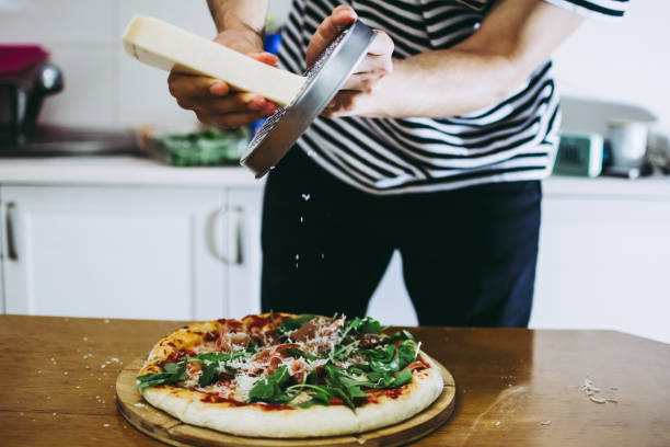 istock Chef rubbing parmigiano cheese over raw pizza dough 1191619507