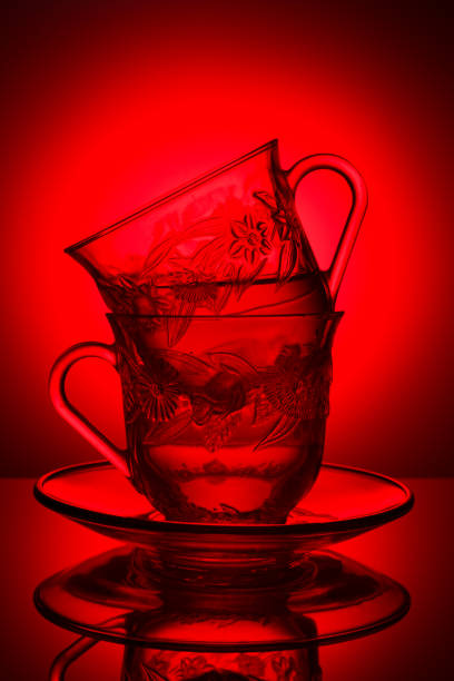 Two glass cups with a pattern, with fragrant tea on a red background, concept of cups.