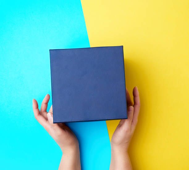 istock two female hands hold a closed dark blue paper cardboard box 1191621148