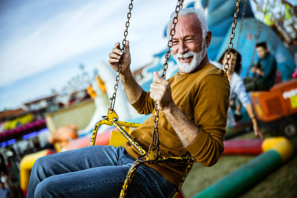 istock Happy senior man having fun while riding on chain swing at amusement park. 1191625459