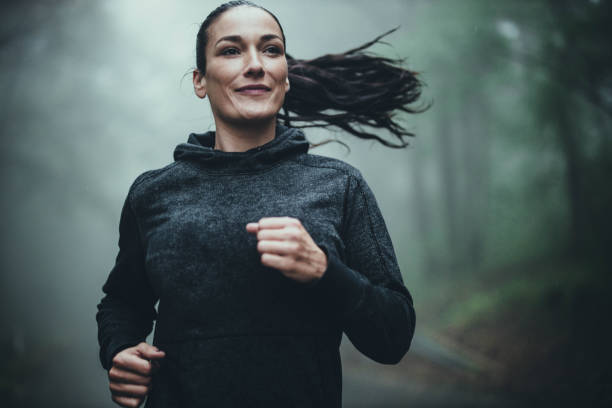 森の霧の日にジョギングを�している笑顔の運動選手。 - fog forest morning autumn ストックフォトと画像