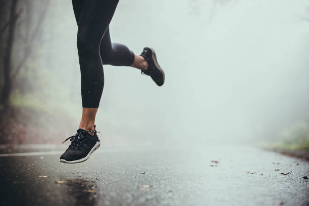 istock Unrecognizable athlete jogging on the road during rainy day. 1191626950