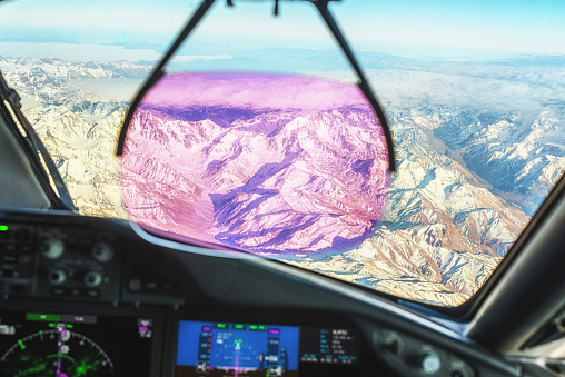 Modern commercial aircraft cockpit with Heads Up Display flying over the Andes near Chili.