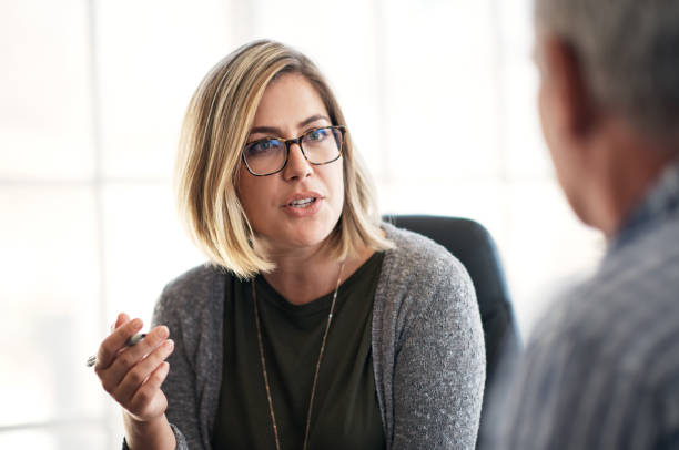 Communication opens the door to growth Shot of a young businesswoman having a discussion with her colleague in a modern office older blonde woman stock pictures, royalty-free photos & images