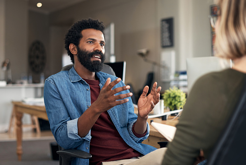 Shot of a young businessman having a discussion with his colleague in a modern office