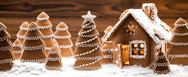 Stock photo showing a close-up view of a homemade, gingerbread house decorated with white royal icing resembling icicles decorated ready for Christmas.