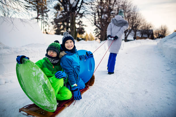 istock Mother pulling kids on toboggan on winter day 1191631504
