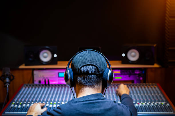powrót azjatyckiego męskiego profesjonalnego producenta muzycznego, inżynier dźwięku mieszający piosenkę na konsoli miksowania audio w studiu nagraniowym. produkcja muzyczna, koncepcja postprodukcji - control room audio zdjęcia i obrazy z banku zdjęć