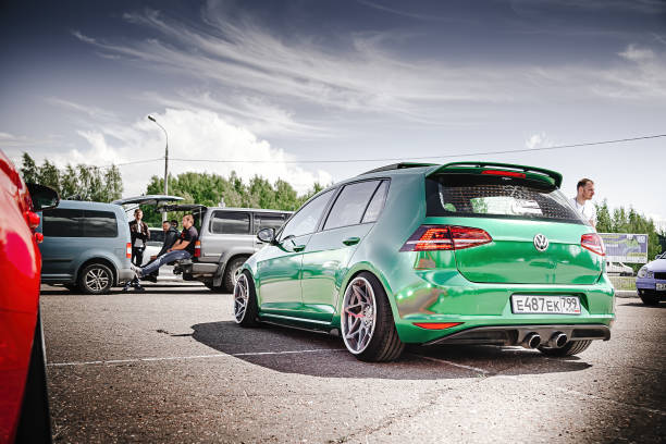 Tuned Volkswagen Golf 7 tightened into a green vinyl film. Installed exclusive wheels, air suspension. Lowrider in the parking lot. Back side view stock photo
