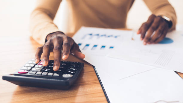African american accountant calculating budget of the company Budget Planning. Unrecognizable black businessman using calculator, tracking income and expenses. Panorama, copy space rich black men pictures stock pictures, royalty-free photos & images