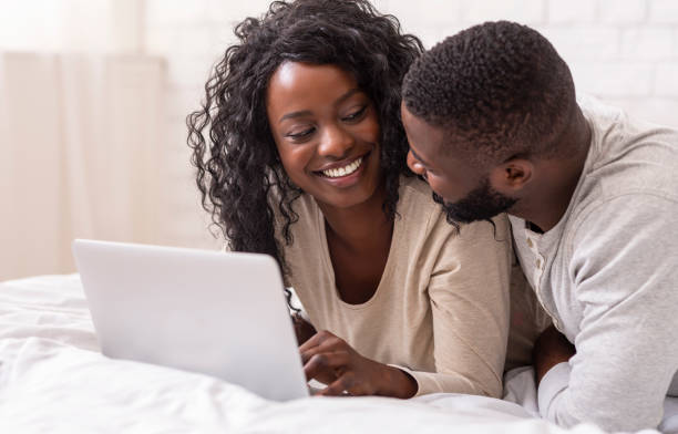 istock Smiling young couple using laptop in bed at home 1191635074