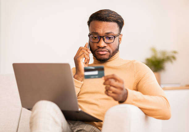 istock Guy Calling By Phone Using Credit Card And Laptop Indoor 1191635996