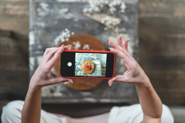 Young adult food stylist woman taking photo on smartphone Cropped view of young adult food stylist using modern smartphone, making content for social media blog, taking photo of sweet dessert influencer photos stock pictures, royalty-free photos & images