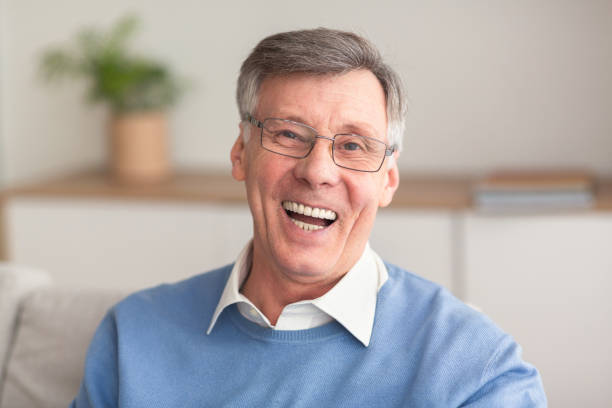 istock Senior Man Laughing At Camera Sitting On Couch At Home 1191636434