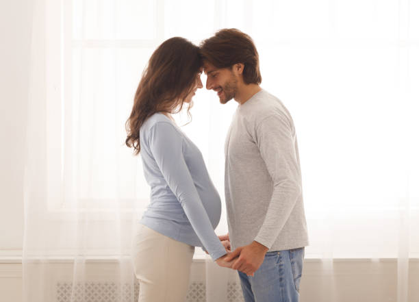 istock Romantic couple expecting baby, holding hands and touching foreheads 1191637407
