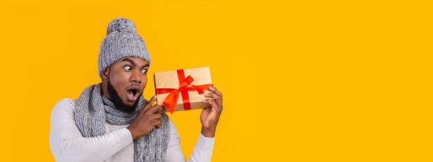 istock Excited afro man with xmas gift looking at copy space 1191637611